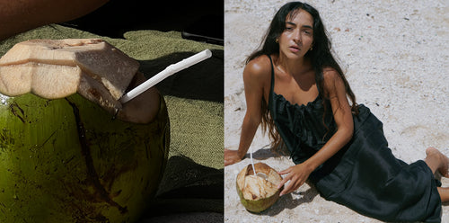 LILLY PILLY woman wearing black Nova silk linen slip reclining with a coconut on the sandy beach